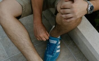 A man sitting on a ledge tying his shoes