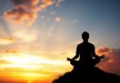 Osoba medytująca na tle zachodu słońca, symbolizująca duchową podróż i jak sprawdzić swój poziom duchowy