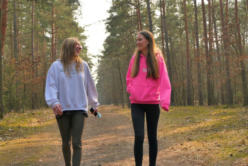 two girls walking down a path in the woods